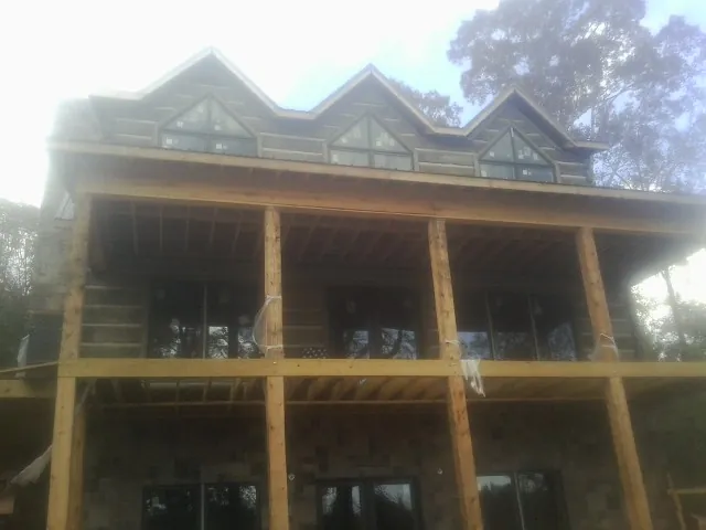 Dormers and porch framing on a large log home under construction — Roof Coating work by our crew in New Richmond