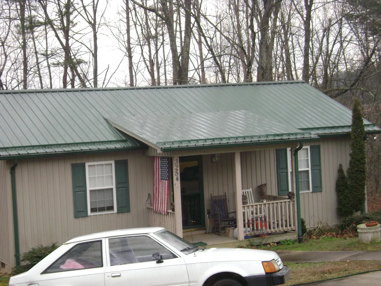 Green metal roof and front porch on a tan sided cottage in New Richmond